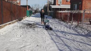 冬天。 年轻妇女和儿童在玩雪橇